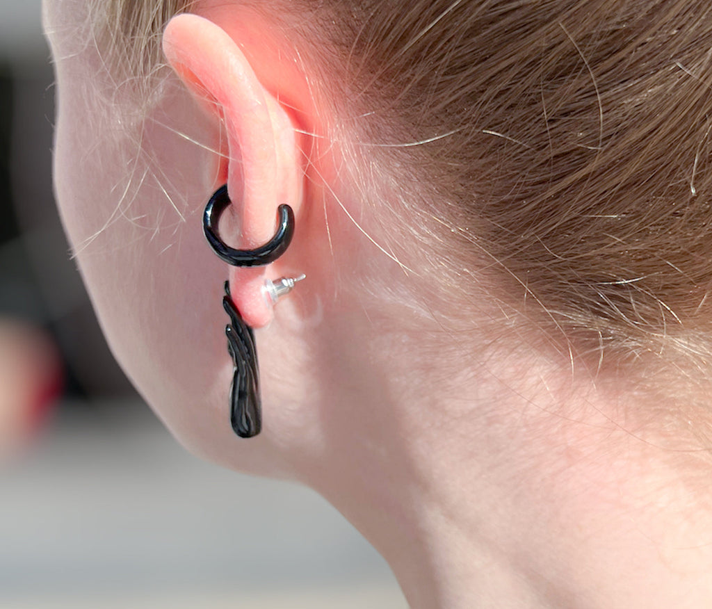 left hand shaped stud earring in black enamel with palm facing outward with black ear cuffon ear